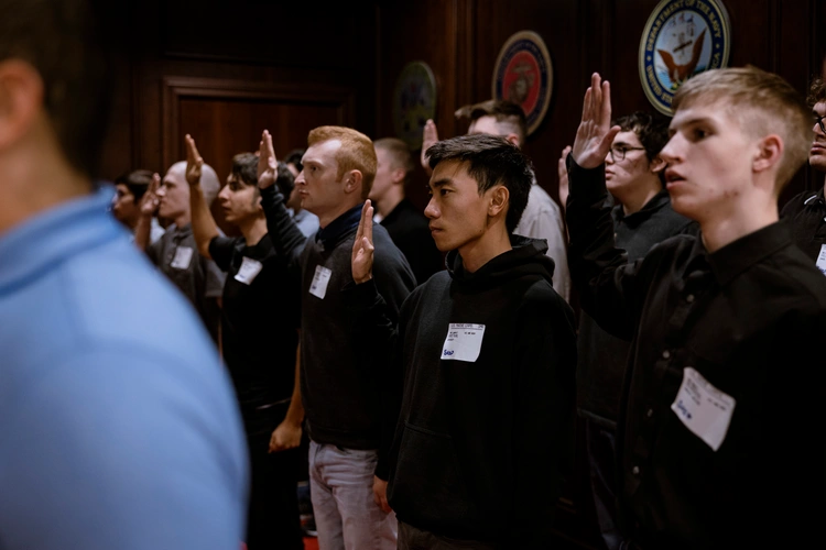 Young recruits taking the oath of enlistment at MEPS, raising their right hands during the swearing-in ceremony